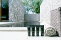 Blank Label of Mini plastic tube with cosmetic products and towels and basket beside swimming pool against sun light. Hotel