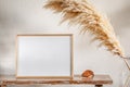 30x40 cm photo frame on a bench with pampas grass near the wall