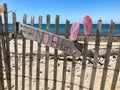 A hand painted sign and a pink pair of children`s sneakers are attached to a fence