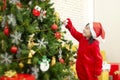 X-mas and holiday. The girl is hanging the decorative socks on the Christmas tree in the living room. Children in santa hat hand Royalty Free Stock Photo