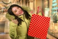 Young happy and beautiful Asian Korean woman holding red shopping bag buying Christmas present in city mall smiling excited and Royalty Free Stock Photo