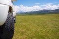 4x4 offroad truck on green mountain valley with mountains and cloudy sky on background . Summer off-road trip Royalty Free Stock Photo