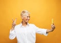 Image of cheerful mature old woman standing isolated over yellow background wall talking by mobile phone. Royalty Free Stock Photo
