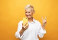 Image of cheerful mature old woman standing isolated over yellow background wall talking by mobile phone. Royalty Free Stock Photo