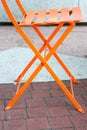 X-shaped orange metal folding chair