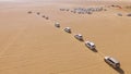 4x4 SUVs cars driving through the sand dunes in the desert of Abu Dhabi. Stock. Top view on SUVs in the desert