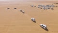 4x4 SUVs cars driving through the sand dunes in the desert of Abu Dhabi. Stock. Top view on SUVs in the desert