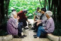 Elderly chinese man and woman playing cards and chatting in a park next to a small pond Royalty Free Stock Photo