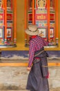 XIAHE, CHINA - AUGUST 25, 2018: Devotee passes a row of praying wheels around Labrang Monastery in Xiahe town, Gansu Royalty Free Stock Photo