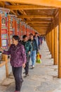XIAHE, CHINA - AUGUST 25, 2018: Devotees pass a row of praying wheels around Labrang Monastery in Xiahe town, Gansu Royalty Free Stock Photo