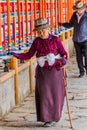 XIAHE, CHINA - AUGUST 25, 2018: Devotees pass a row of praying wheels around Labrang Monastery in Xiahe town, Gansu Royalty Free Stock Photo