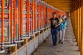 XIAHE, CHINA - AUGUST 24, 2018: People pass a row of praying wheels around Labrang Monastery in Xiahe town, Gansu Royalty Free Stock Photo