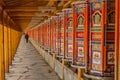 XIAHE, CHINA - AUGUST 24, 2018: People pass a row of praying wheels around Labrang Monastery in Xiahe town, Gansu Royalty Free Stock Photo