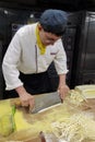 On the production stage, a pastry master is making noodles with a knife.