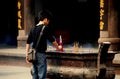 Xindu, China: Man Lighting Incense Sticks