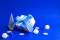 Xmas background blue. White gift box with blue ribbon, winter tree, Snowflakes and Silver balls in Christmas composition on blue Royalty Free Stock Photo