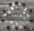 Xmas handmade wood toys, and red balls, creating a circle. Sale text writing, on a wooden gray background