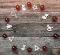 Xmas handmade wood toys, and red balls, creating a circle. Space for text writing, on a wooden gray background