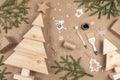 XMAS or New Year composition. Wooden Christmas trees, paint, brushes and fir branches on craft beige background. Concept