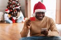 Xmas Online Shopping. Black man using cellphone showing credit card