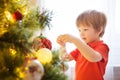 Xmas party celebration. Child decorating Christmas tree at home. Family with kids celebrate winter holidays. New year small boy at Royalty Free Stock Photo