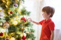 Xmas party celebration. Little boy decorating Christmas tree with toy balls Royalty Free Stock Photo