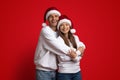 Xmas Romance. Loving Young Couple Wearing Santa Hats Embracing On Red Background Royalty Free Stock Photo