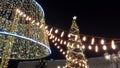 Xmas sparkles. Christmas eve. Glow of Christmas lights hanging on garland against huge Christmas tree. Low Winde angle