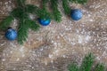 Xmas tree branches, blue balls on winter snowbound wooden background