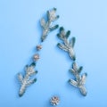 Xmas tree shape made of snowy fir branch and pinecone. Square composition, flat lay, view from above. Classic blue background. Royalty Free Stock Photo