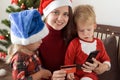Xmas, winter, new year, Celebration, family concept - joyful mom doing shopping online with two small funny kids sit Royalty Free Stock Photo
