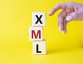 XML - Extensible Markup Language. Wooden cubes with word XML. Businessman hand. Beautiful yellow background. Business and