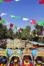 Xochimilco, Colourful chinampas and trajineras with papel picado on a blue sky and trees in Mexico City