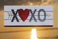 XOXO Hugs and Kisses wooden sign with Red Heart at the sunrise in front of the lake. Love, Romance and Friendship