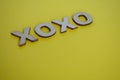 XOXO wooden letters representing Hugs and Kisses on yellow background