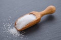 Xylitol or birch sugar in a wooden scoop on black background, selective focus