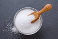 Xylitol or birch sugar in a wooden scoop and glass bowl on black background, selective focus