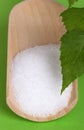 Xylitol birch sugar on wooden scoop over green