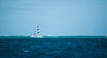 Yacht with blue and white sail far in the distance in Hawaii