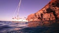 Yacht boat in the blue ocean water near the cliff on the background