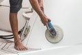 Yacht maintenance. A man polishing side of the white boat in the Royalty Free Stock Photo