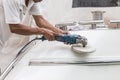 Yacht maintenance. A man polishing side of the white boat in the Royalty Free Stock Photo