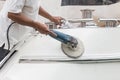 Yacht maintenance. A man polishing side of the white boat in the Royalty Free Stock Photo