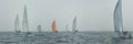 Yacht regatta at sea during the rain and orange sail in a foggy morning floats on the sea. Wide panorama Royalty Free Stock Photo