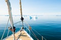 Yacht sailing among icebergs in Atlantic ocean in Greenland