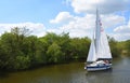 Yacht under sail navigating the river Bure near Horning, the Norfolk Broads.