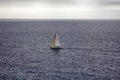 Small single-masted sailing yacht on background of weak waves