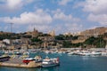 Yachts, boats and ships in Mgarr harbour, at Gozo, Malta, with Lourdes Chapel and Ghajnsielem Parish Church on the hill.