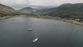 Yachts, boats, ships at Scotland ocean bay aerial. Epic mountains landscape on cloudy summer day