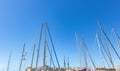 Yachts mast tops against the clear blue sky at marina Zeas, Greece. Vertical lines with ropes, city background Royalty Free Stock Photo